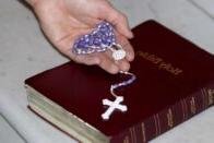 A photo of someone holding a rosary with a Holy Bible.